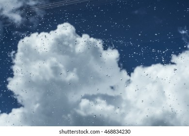 Rainy sky with white clouds, and raindrops on the window