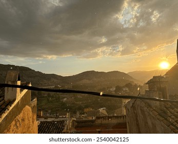 Rainy view from rooftop in Cehegín Spain, with a beautiful sunset and cloudy sky over mountains, forest, church and village - Powered by Shutterstock