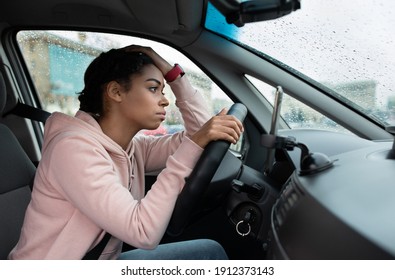 Rainy Weather, Problems On Road And Traffic Jams. Sad Tired Millennial African American Lady With Smartwatch At Steering Strapped Up, With Hand On Head, Looks At Wet Window, Side View, Free Space