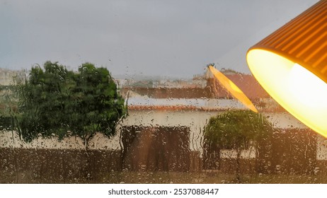 Rainy window view with warm interior lamp reflection in foreground - Powered by Shutterstock