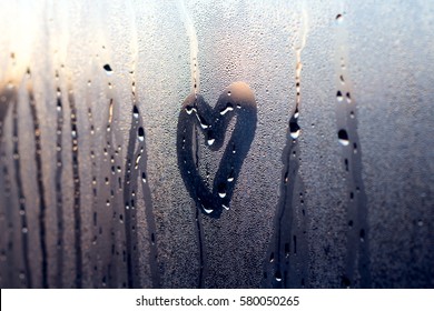 A rainy winter day seen through a wet window a moment before sunset with heart