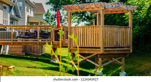 Raised Backyard Wooden Deck And Gazebo In A Treed Backyard, Behind A Row Of Houses