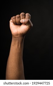 Raised Fist Of A Black Man, On Black Background.