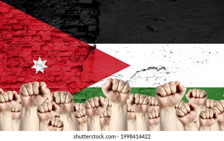 Raised fists of men against the background of the flag of Jordan painted on the wall, the concept of popular unity and the opinion of the majority. - Shutterstock ID 1998414422