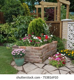 Raised Flower Bed And Summer Flowers In English Town Garden.