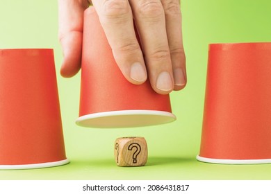 Raised Glass And Wooden Cube With Question Mark Symbol Underneath, Thimble Game Concept And Its Harm