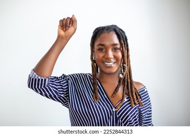 Raised hand of young African woman clenched into fists on light background. Stop racism concept - Shutterstock ID 2252844313