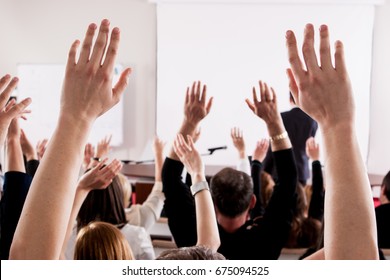 Raised hands and arms of large group of people in class room, audience voting in professional education surrounding, selective focus with anonymous people. - Shutterstock ID 675094525