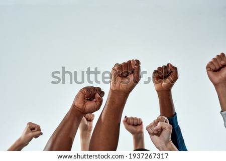 Raised hands of multiracial people clenched into fists on light background. Stop racism concept