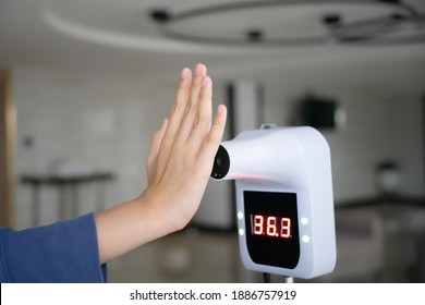 Raising Hand Close To Digital Infrared Thermometer   For Check Temperature Measurement Screening From COVID-19 For Check In Building ,hotel ,restaurant Or Lobby , In Soft Focus