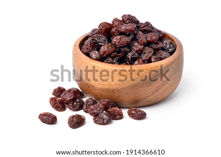 Raisins in wooden bowl isolated on white background.