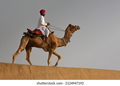 Rajasthan India February 2020: A Nomadic Camel Herder Rides In The Early Morning Light In The Thar Desert