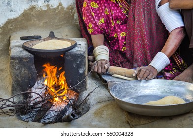 RAJASTHAN, INDIA - NOVEMBER 20, 2016: Indian Poor Woman In Village Cooking Food With Traditional Way Of Baking Chapati On Wood Fire Stove (chulha) In The Courtyard Of Her House For Family.