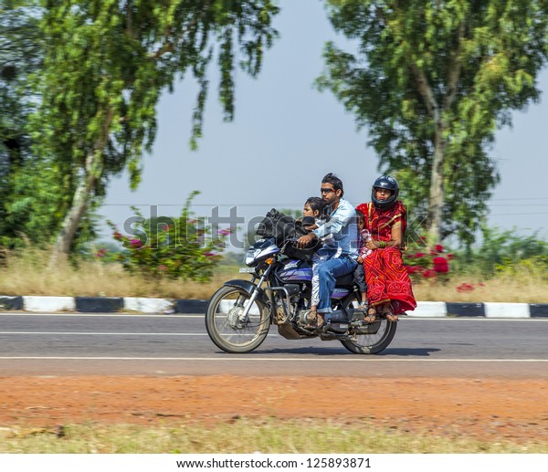 RAJASTHAN, INDIA - OCTOBER 18: Mother, father\
and small child ride on scooter at highway street on October 28,\
2012 in Rajasthan, India. Up to six family members manage to ride\
these two wheelers.