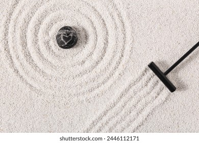 Rake and stone on sand with lines in Japanese rock garden, top view.  Zen concept - Powered by Shutterstock