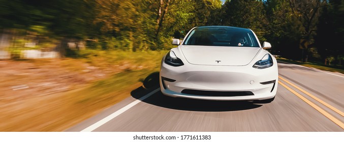 RALEIGH, NC USA, APRIL 17, 2020: A New Tesla Model 3 All Electric Vehicle Driving Down A Country Road