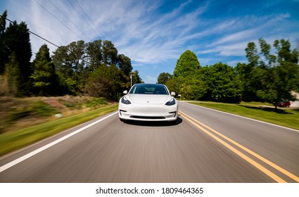 RALEIGH, NC USA, APRIL 17, 2020: A New Tesla Model 3 All Electric Vehicle Driving Down A Country Road