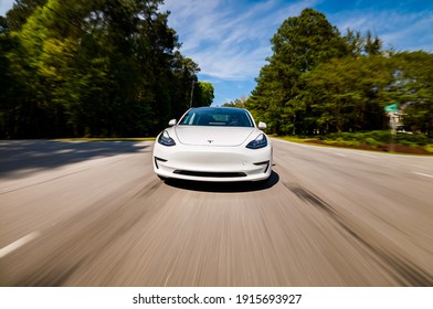 RALEIGH, NC USA, APRIL 17, 2020: A New Tesla Model 3 All Electric Vehicle Driving Down A Country Road