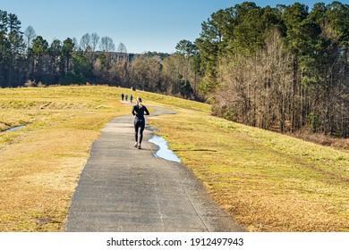 Raleigh, North Carolina USA-02 08 2021: A Woman Jogs On The Lake Crabtree Trail In Winter.