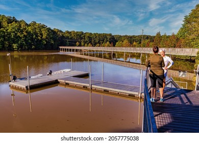 Raleigh, North Carolina USA-10 14 2021: Two Ladies Talk On A Dock Overlooking Lake Johnson And The Boardwalk.