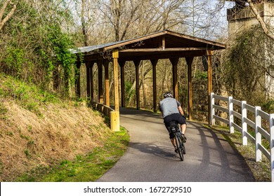 Raleigh,NC/USA-3/14/20: Neuse River Trail In March. A Cyclist Nears The Covered Bridge.