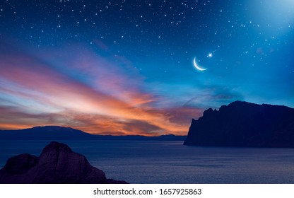 Ramadan background with crescent, stars and glowing clouds with ray from skies above mountains and sea. Month of Ramadan is that in which was revealed Quran. Elements of this image furnished by NASA