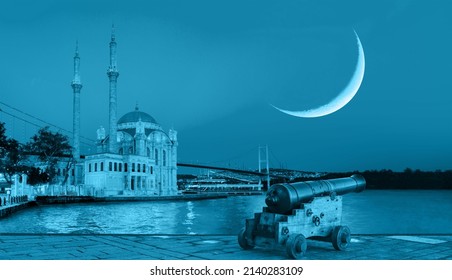 Ramadan Concept - Ortakoy mosque and Bosphorus bridge with crescent and cannon at twilight blue hour - Istanbul, Turkey