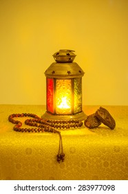 Ramadan festive background. Traditional ramadan lamp with date fruit and islamic prayer beads. Bright golden yellow color scheme. 