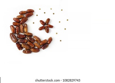 Ramadan, iftar table composition. Dried date fruit arranged in moon and star shape, golden confetti on white background. Party decoration. Food pattern. Empty space. Flat lay, top view. 