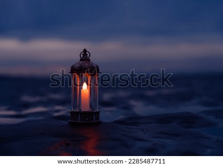 Ramadan Kareem, Arabic lantern with burning candle on sand beach with blurry sunset sky background.Image for Festive greeting card,invitation for Muslim holy month,Eid Mubarak,Eid al Adha,Eid al Fitr 