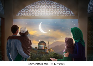 Ramadan Kareem Gruß. Familie im Fenster mit Blick auf die islamische Stadt mit Moschee Skyline, Halbmond und Sterne. Muslime Eltern und Kinder beten. Mutter, Vater und Kinder feiern das Ende des Fastens. 