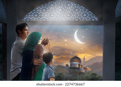 Ramadan Kareem greeting. Family at window looking at Islamic city with mosque skyline, crescent moon and stars. Muslim parents and children pray. Mother, father and kids celebrate end of fasting.  - Powered by Shutterstock