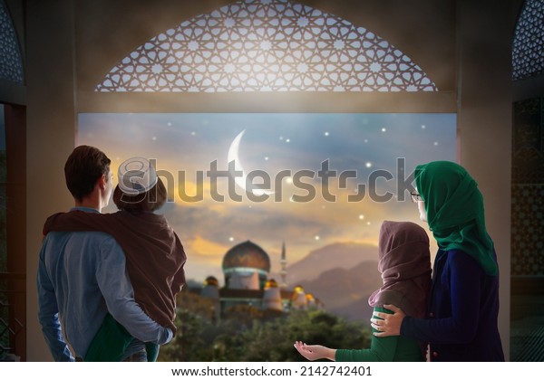 Ramadan Kareem greeting. Family at window looking at\
Islamic city with mosque skyline, crescent moon and stars. Muslim\
parents and children pray. Mother, father and kids celebrate end of\
fasting. 