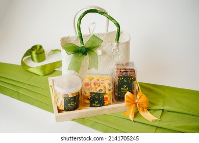 Ramadhan gift. Hampers moslem theme for celebrete the holy, bake snack, nastar, bakery, cookies, pudiing, chococips, roll cake, castangel.with greeting card and green accessories on white background - Shutterstock ID 2141705245