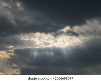 ramatic cloudy sky with sun rays breaking through dark storm clouds