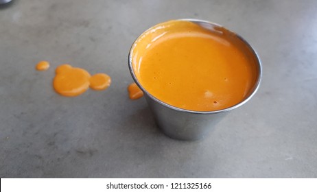 Ramekin With Orange Sauce On A Concrete Table. Drops Of Sauce On The Table.