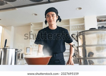 A ramen shop clerk offering a bowl of noodle.