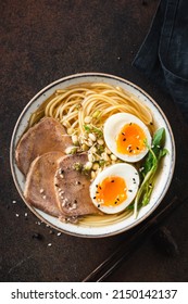 Ramen soup noodle bowl with egg and meat on dark brown background, table top view. Asian cuisine food - Shutterstock ID 2150142137
