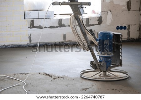Ramming and grinding of semi-dry floor screed by a machine with a rotating disk for leveling. Construction of a concrete floor in the house, a master with special equipment. Stock photo © 