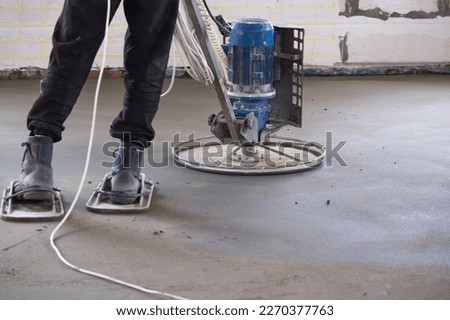 Ramming and grinding of semi-dry floor screed by a machine with a rotating disk for leveling. Construction of a concrete floor in the house, a master with special equipment. Stock photo © 