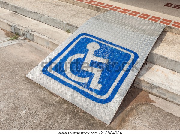 Ramped access, using\
wheelchair ramp with information sign on floor background for\
disabled people.