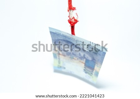 The rand is hanging by a thread and close to collapse on red damaged rope on white background