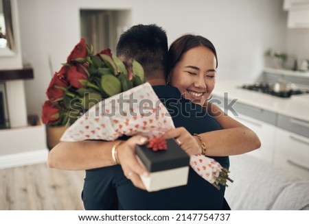 Random acts of kindness. Shot of a young man surprising his wife with flowers at home.
