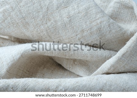 Randomly folded hemp fabric. Rough, undyed hemp canvas. Selective focus.