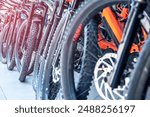 Range of bicycles lined up in a store, highlighting mountain bikes and electric bikes with vividly colored frames and sophisticated mechanical parts, ideal for cycling enthusiasts and professionals.