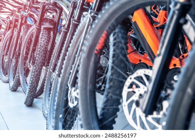 Range of bicycles lined up in a store, highlighting mountain bikes and electric bikes with vividly colored frames and sophisticated mechanical parts, ideal for cycling enthusiasts and professionals. - Powered by Shutterstock