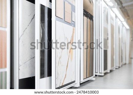 Range of natural and technical stone tile samples in different colors and textures displayed on sliding panels in showroom, showcasing design options for interiors