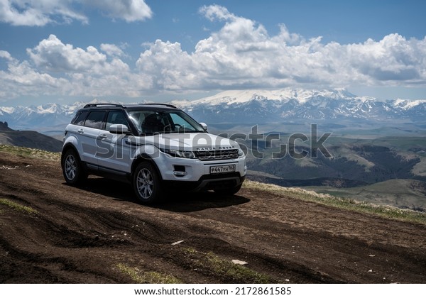 Range Rover Evoque car on the background of the\
mountains of the North Caucasus in Russia. A clear sunny day on May\
30, 2022