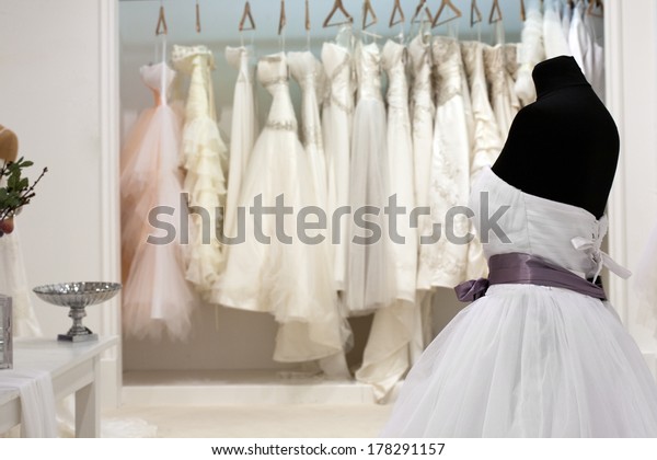 The range of wedding dresses on hangers and on a\
mannequin in the showroom