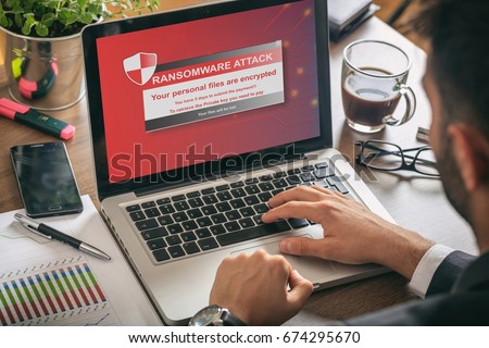 Ransomware alert message on a laptop screen - man at work